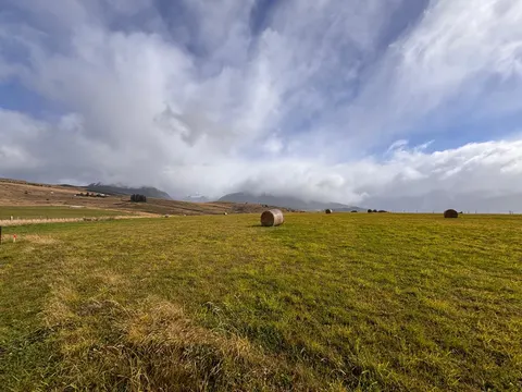 Flat, cleared plot of 5,000 m² with native grass and distant hills